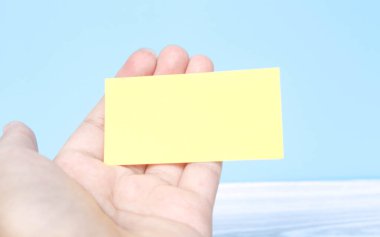 Avuç içi kağıdı tutar. Mavi arka planda avuç içi boş kağıt. Avuç içine yazı yazmak için boş bir sayfa. Metin ve reklamlar için boş alan