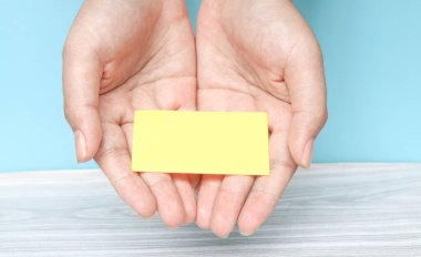 Avuç içi kağıdı tutar. Mavi arka planda avuç içi boş kağıt. Avuç içine yazı yazmak için boş bir sayfa. Metin ve reklamlar için boş alan