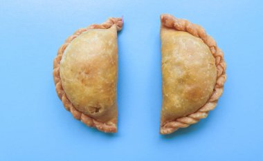 Körili puf ve kızarmış Pastel ya da kızarmış sebze, tavuk ve haşlanmış yumurtalarla dolu kuru hamur işi mavi arka planda izole edilmiş.