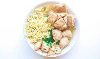 Beyaz arka planda beyaz bir kasede servis edilen erişte, tofu, kereviz ve yumurta içeren Endonezya usulü çorba köfteleri. Kasede sos olan köfteleri kapat.