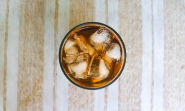 Ahşap masada izole edilmiş büyük bardakta buzla dolu buzlu çay bardağını kapat. Yukarıdan taze buzlu çay manzarası