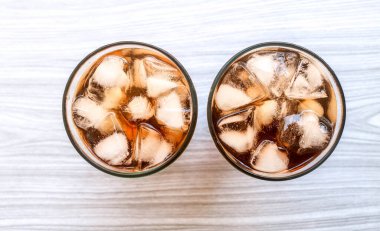 Ahşap masada izole edilmiş büyük bardakta buzla dolu buzlu çay bardağını kapat. Yukarıdan taze buzlu çay manzarası