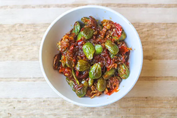 stock image Sambal Pete or petai with small shrimps served in a white bowl on the table. Sambal or popular Indonesian sauce.