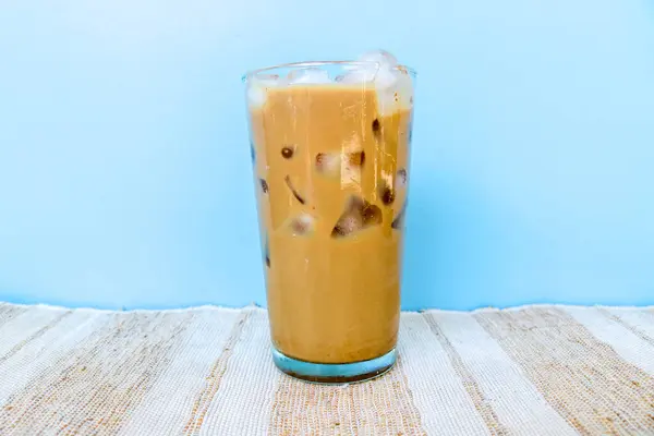 Buzlu moka kahvesi mavi arka planda izole edilmiş buzla dolu uzun bir bardakta. Taze mocha buzlu kahve.