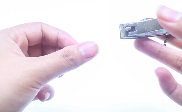 Kadın elinin tırnaklarını keserken ya da manikür yaparken ya da beyaz arka planda bulunan tırnak makasını kullanarak kendi kestiği parmağını kapat.