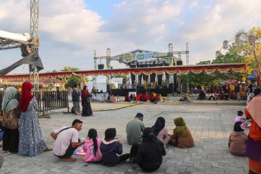 Endonezya - 29 Eylül 2024: Eğlence fuarı sahnesinin önünde oturan bir grup insan, bir dans gösterisi