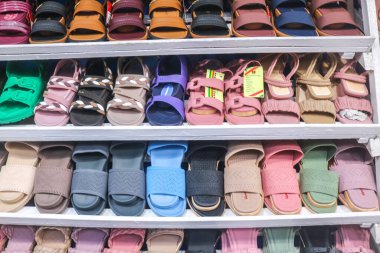 Endonezya - 29 Eylül 2024: Alışveriş merkezinde çeşitli parmak arası terlik ve ayakkabılar satan mağazalar, mağazalarda renkli şirin sandaletler