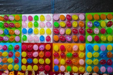 Lunaparkta ödül kazanmak için balon okçuluğu oyunu. Duvarda renkli balonlar var.