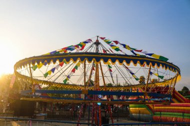Öğleden sonra eğlence parkında gün batımında atlı karınca gezintisi, eğlence festivali. Atlıkarıncanın boş koltukları gece pazarında geziniyor.