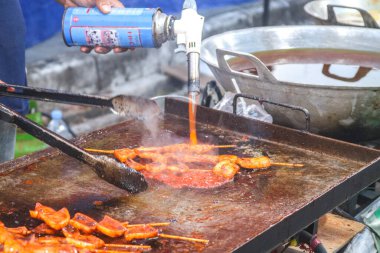 Şefin ellerini mangalda sosis, ızgara kalamar, barbekü, ızgarada meşale ateşiyle yakın. Barbekü sokak yemeği.