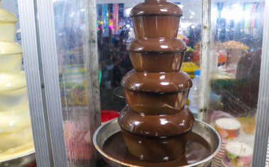 Meyve ve marşmelov daldırmak için sergilenen kutuda çikolata çeşmesi var. Bardakta çikolata çeşmesi