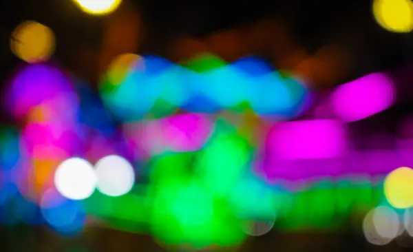 Gece festivalinde Bokeh arka planlı bir lunaparktaki atlı karınca turunun bulanık görüntüsü. Gece festival parkındaki eğlenceli gezintilerin gece renkli ışıklarla çekilmiş soyut bulanık fotoğrafı..