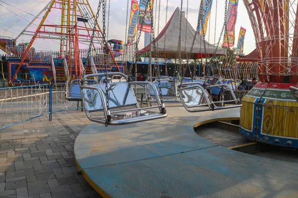 Öğleden sonra eğlence parkında gün batımında atlı karınca gezintisi, eğlence festivali. Atlıkarıncanın boş koltukları gece pazarında geziniyor.