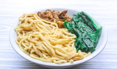 Mie ayam (Erişte Tavuğu), Endonezya 'nın tipik bir eriştesi olup, kıyılmış tavuk ve haşlanmış hardal yeşili ile birlikte gri ahşap bir masada soya sosu ile servis edilir.