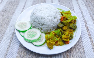 Köri soslu sığır eti, beyaz tabakta pirinçle servis edilen sebzeler ve baharatlarla süslenmiş. Biftek maşası lahana, arnavut biberi, domates parçaları içerir..