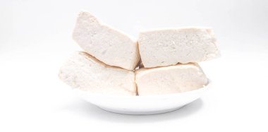 Beyaz arka planda beyaz bir tabakta taze beyaz tofu küpleri. Taze soya fasulyesi..