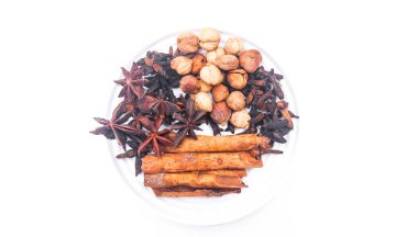 Kakule, tarçın, yıldız anason, anason tohumu, karanfil, kişniş tohumu, beyaz arka planda izole edilmiş. Doğal baharatları bir tabakta toplayın