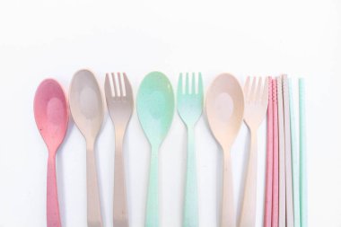 Araçlar beyaz arkaplana renkli çatal, yemek çubuğu ve kaşık yerleştirildi