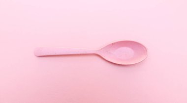 Pembe arka planda izole edilmiş farklı renkli plastik kaşıklar. Renkli kaşık takımı