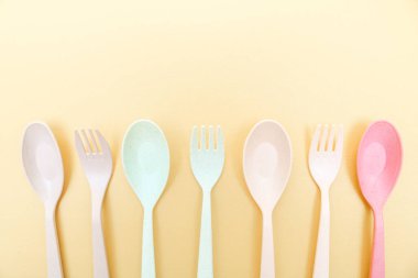 Utensiller sarı arka planda izole edilmiş renkli çatal, yemek çubuğu ve kaşık seti