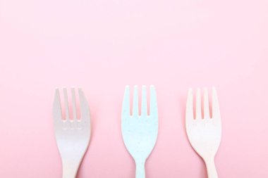 Pembe arka planda üç renkli çatal. Boş alanı olan renkli çatal bıçak takımı