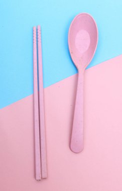 Araçlar mavi arkaplanda renkli çatal, yemek çubuğu ve kaşık izole edilmiş.