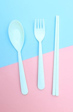 Araçlar mavi arkaplanda renkli çatal, yemek çubuğu ve kaşık izole edilmiş.