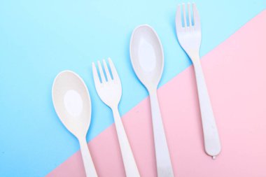 Araçlar mavi arkaplanda renkli çatal, yemek çubuğu ve kaşık izole edilmiş.