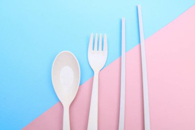 Araçlar mavi arkaplanda renkli çatal, yemek çubuğu ve kaşık izole edilmiş.