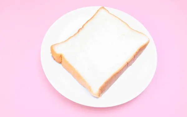 Bir tabakta çilek reçeli ve pembe zemin üzerinde iki dilimlenmiş ekmek ile beyaz ekmek kaplayın. Basit kahvaltı. Reçelli tost..