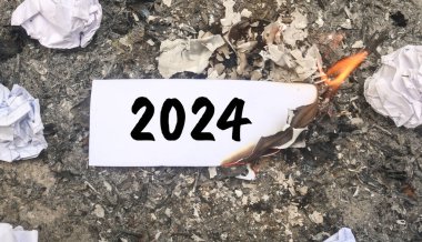 Kağıt yanıyor ve kağıt yığını üzerinde 2024 yazıyor. Yeni hayat ve yeni yıl 2025 konsepti. 2024 kâğıdı yanıyor, 2024 'e veda et.