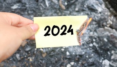 Yanan kağıt ve kağıt yığınının üzerinde 2024 yazılıydı. Yeni hayat ve yeni yıl 2025 konsepti. 2024 kâğıdı yanıyor, 2024 'e veda et.