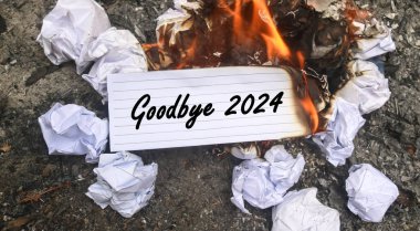 Kağıt alev alev yanıyor ve kağıt yığınında Elveda 2024 yazıyor. Yeni hayat ve yeni yıl 2025 konsepti. 2024 kâğıdı yanıyor, 2024 'e veda et.