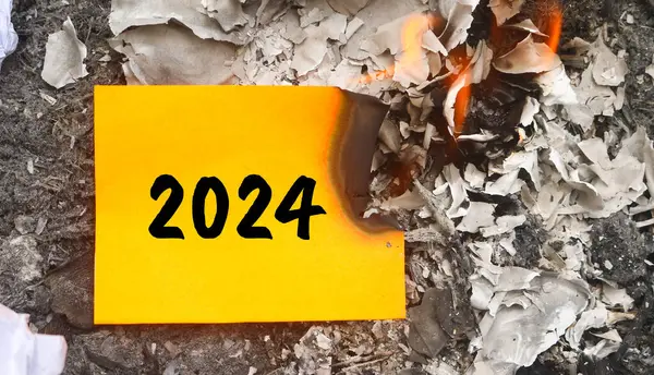 Kağıt yanıyor ve kağıt yığını üzerinde 2024 yazıyor. Yeni hayat ve yeni yıl 2025 konsepti. 2024 kâğıdı yanıyor, 2024 'e veda et.