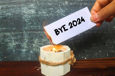 Elinde yarı yanmış bir notla mumunda Bye 2024 yazıyordu. Geçmiş 2024 'ü yakın. 2024 'e elveda de..