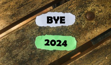 Inscription on the word goodbye 2024 on wooden table background. Bye 2024 on paper, hello 2025 clipart