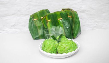 Green sticky rice tape shaped into a circle served on a plate isolated on a white background. Indonesian sticky rice tape wrapped in banana leaves clipart