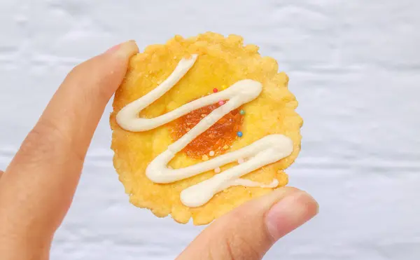 Renkli soslu mini turtalar tutan eller. Beyaz arka planda küçük tart kekleri ve turtalar. Renkli çikolata soslu küçük kapkekler, boş alanı kopyala