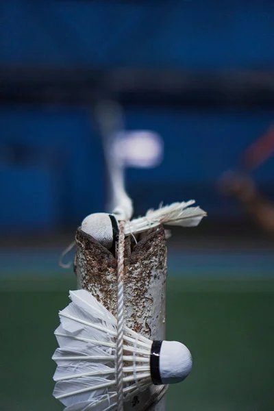 A badminton shuttlecock is caught in the net of the Jambi badminton court, with a blurred background of the players in action