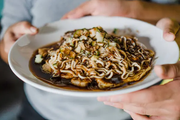 Bir tabak pempek lenggang 'ın süper yakın plan fotoğrafı, eriştenin detaylarını gösteren, küçük salatalık dilimleri ve pempek sirkesi sosu.