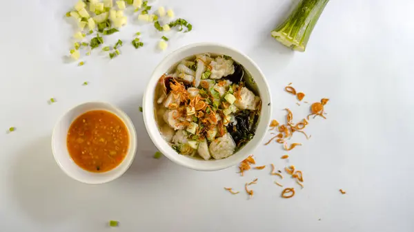 Bir kase biber sosu, salatalık ve kızarmış arpacık soğanı ile süslenmiş tekwan.