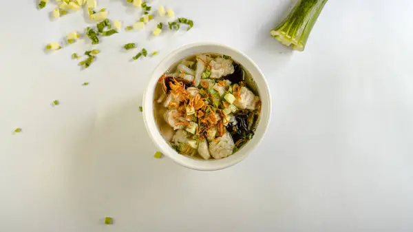 Salatalık dilimleri ve taze soğanla süslenmiş bir kase tekvan çorbası.