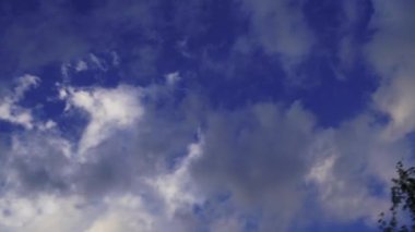 Hızlı hareket eden beyaz kümülüs bulutları. Mavi gökyüzü birkaç katmanlı bulutlarla.