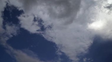 Hareket eden beyaz kümülüs bulutları. Mavi gökyüzü birkaç katmanlı bulutlarla.