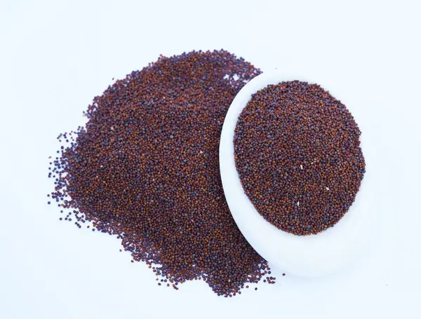 Hardal tohumlarını kapat / Rai veya kahverengi hardal tohumlarını küçük bir tabakta koyu Gotik renklerde beyaz bir yüzeye koy..