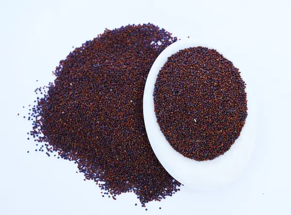 Hardal tohumlarını kapat / Rai veya kahverengi hardal tohumlarını küçük bir tabakta koyu Gotik renklerde beyaz bir yüzeye koy..