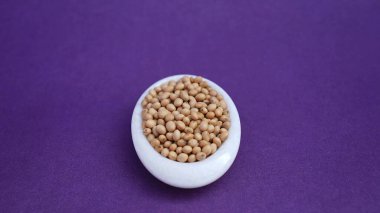 Mor arka planda izole edilmiş beyaz bir tabakta soya fasulyesi. .