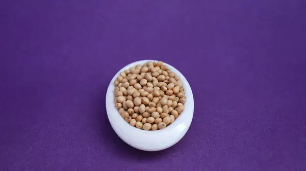 Mor arka planda izole edilmiş beyaz bir tabakta soya fasulyesi. .