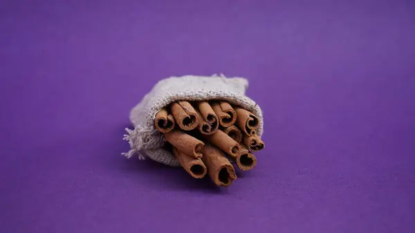 Seylan tarçın. Mor arka planda izole edilmiş tarçın çubukları. Tarçınlı rulo. Fırın, tatlı ve içecekler için baharatlı baharat. Güzel kokulu tarçın. Yakın plan. Mesaj için yer. Boşluğu kopyala