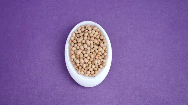 Mor arka planda izole edilmiş beyaz bir tabakta soya fasulyesi. .